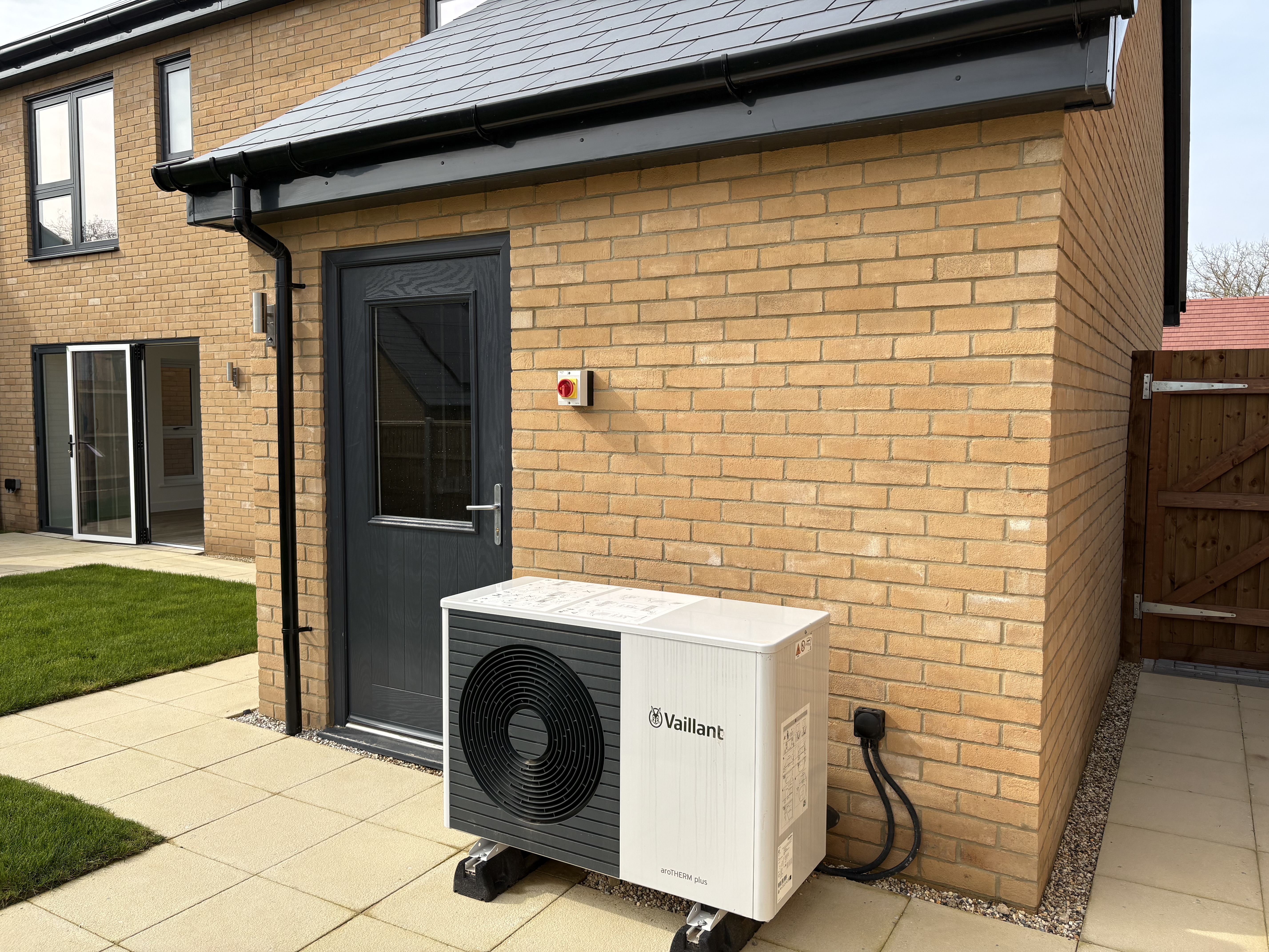 A heat pump on paving outside a door in a new home