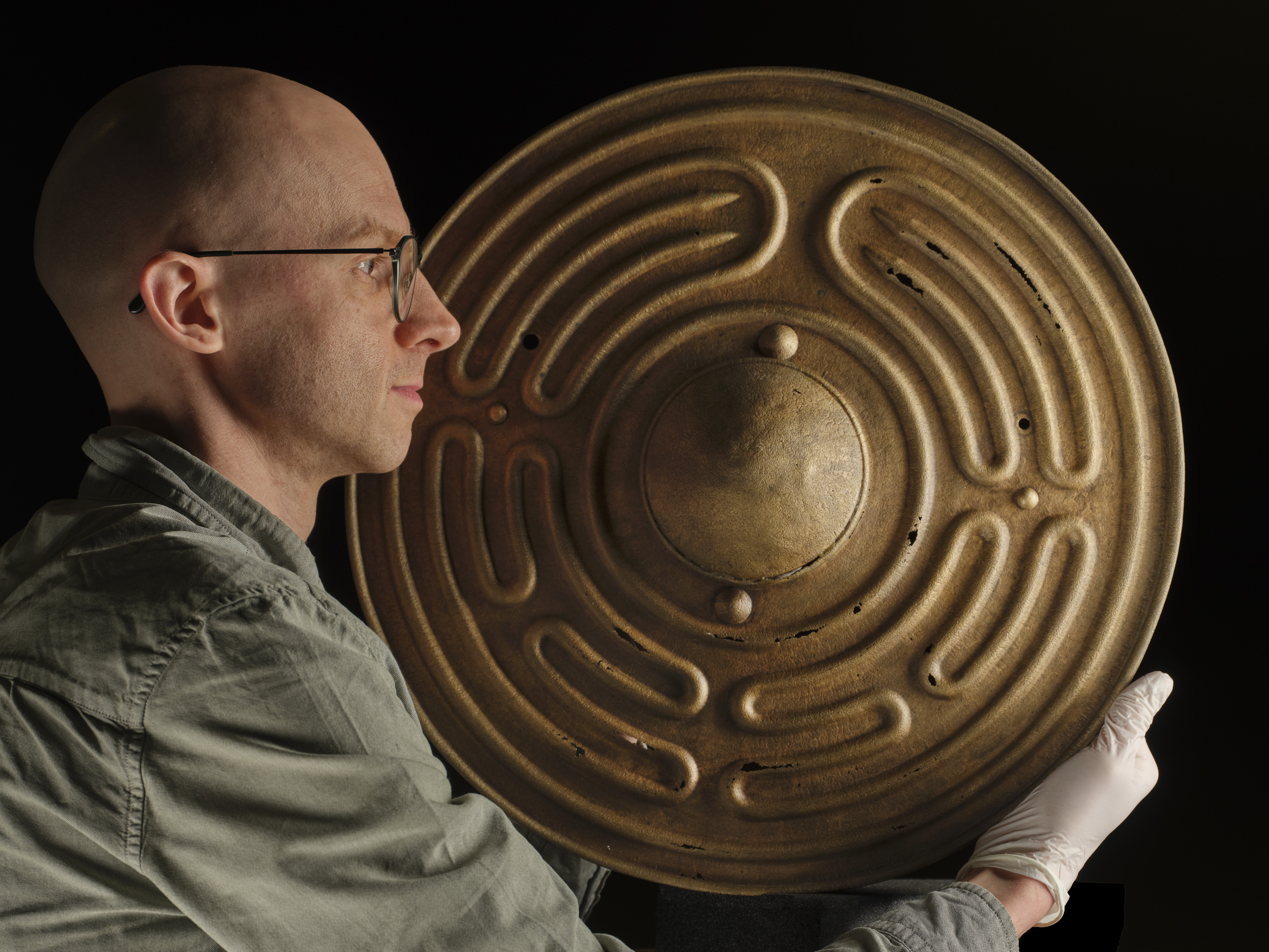 Side view of Matthew Knight holding up a Bronze Age shields