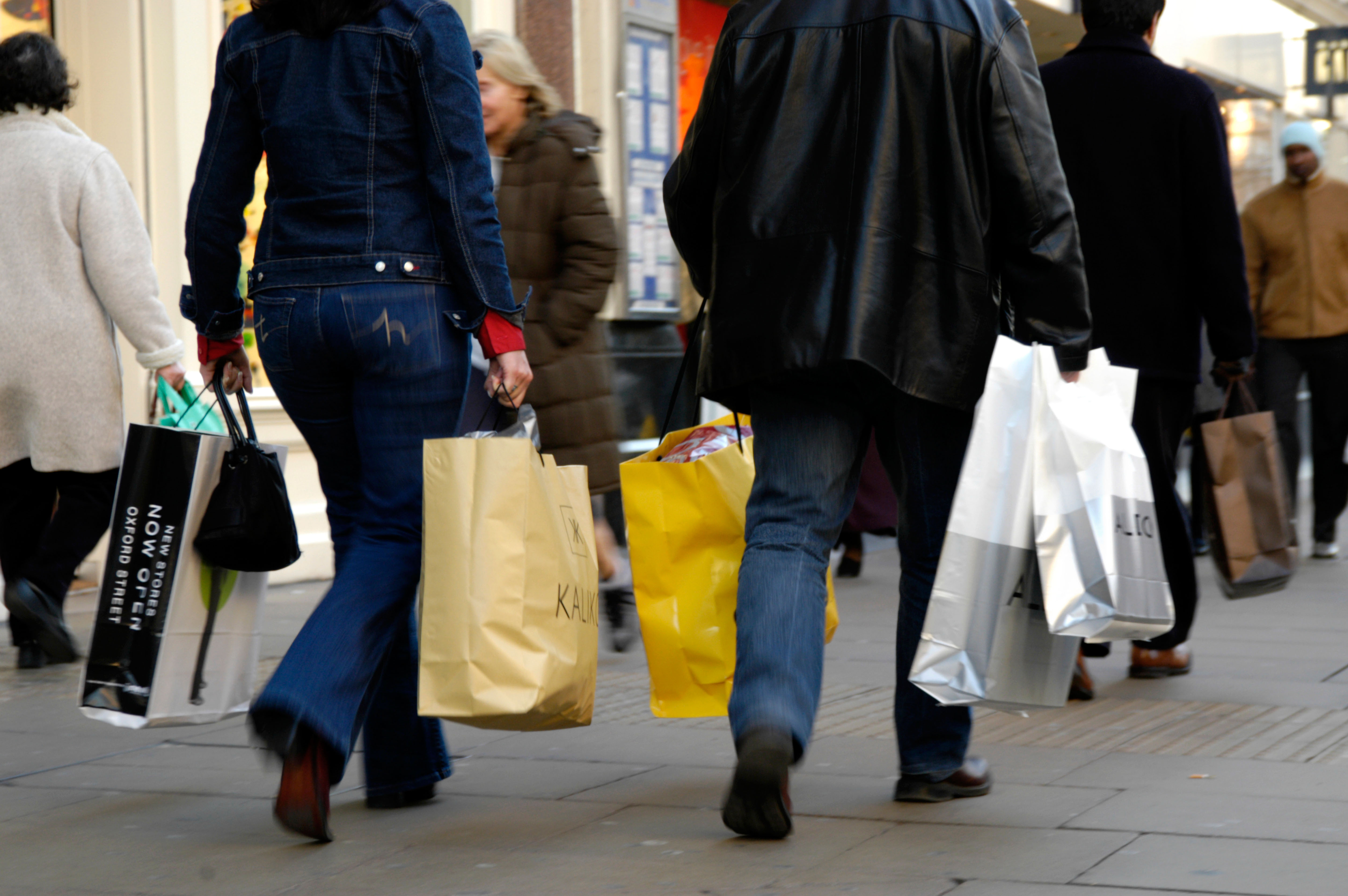 People on a street with shopping bags seen from waist down