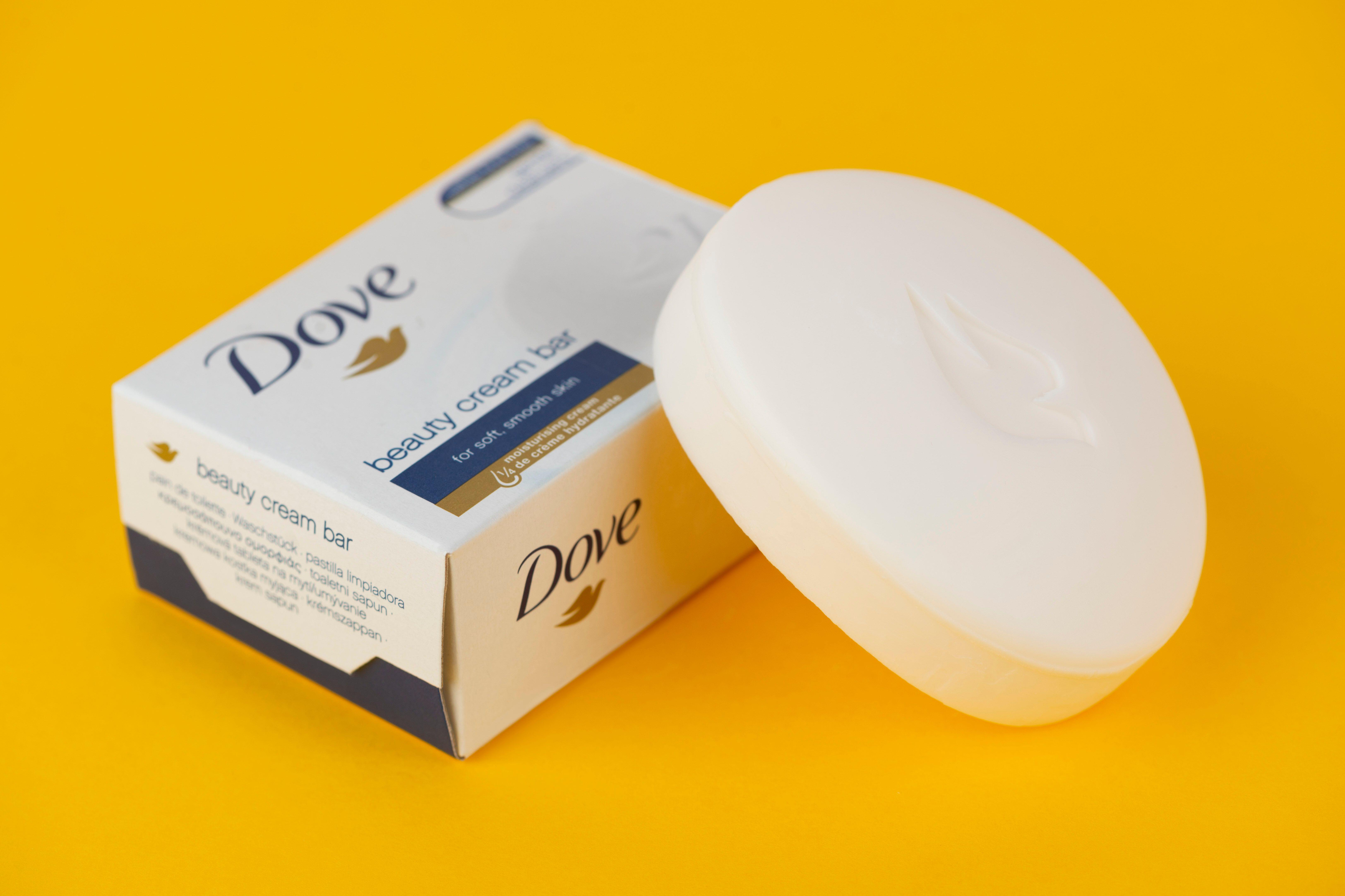 A bar of Dove soap shot on a yellow background along with the product's box packaging