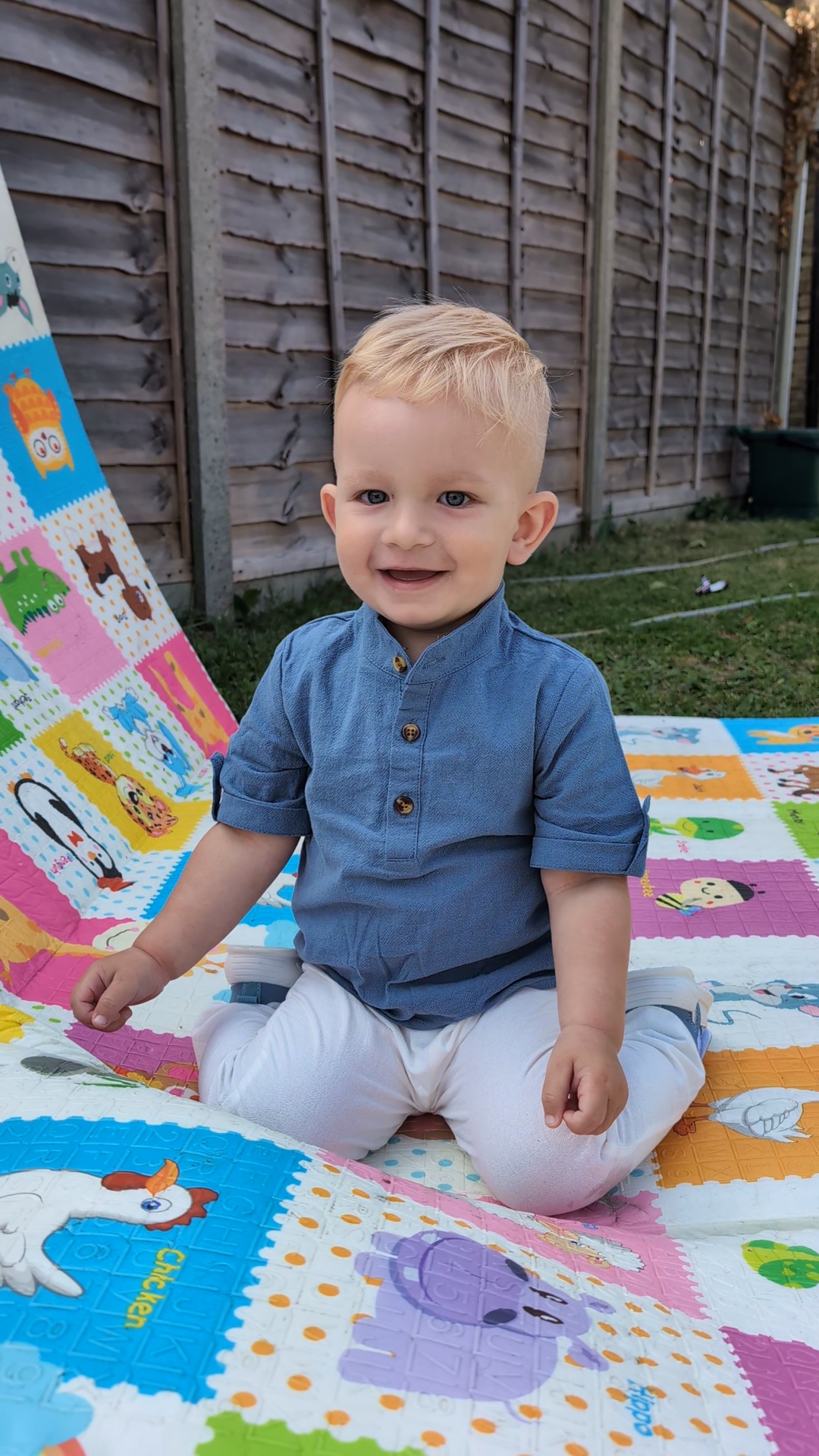 Cezar Nica smiling while sitting on a playmat in a garden