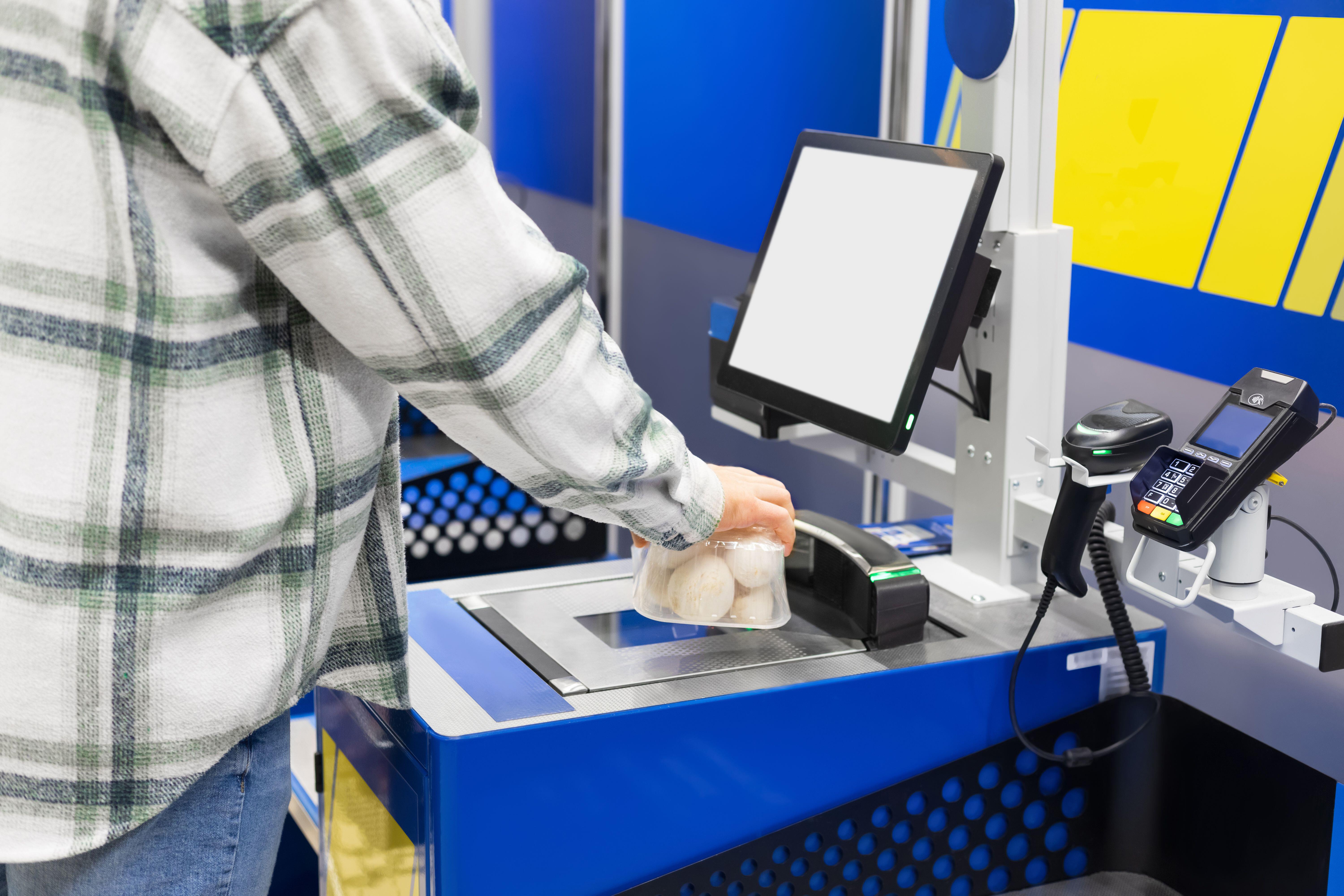 A customer scanning mushrooms at a self-checkout in a supermarket