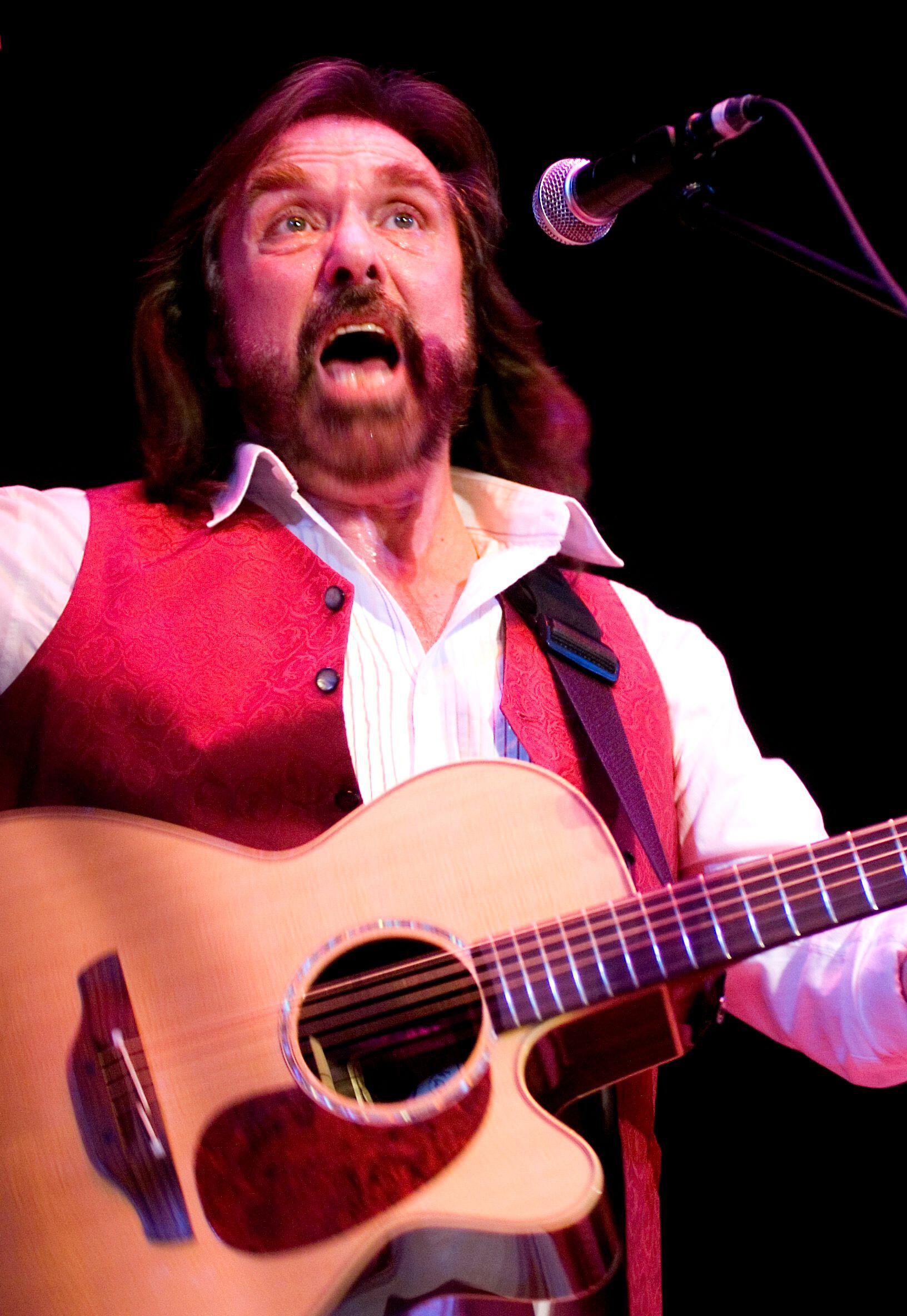 Dennis Locorriere singing and playing a guitar