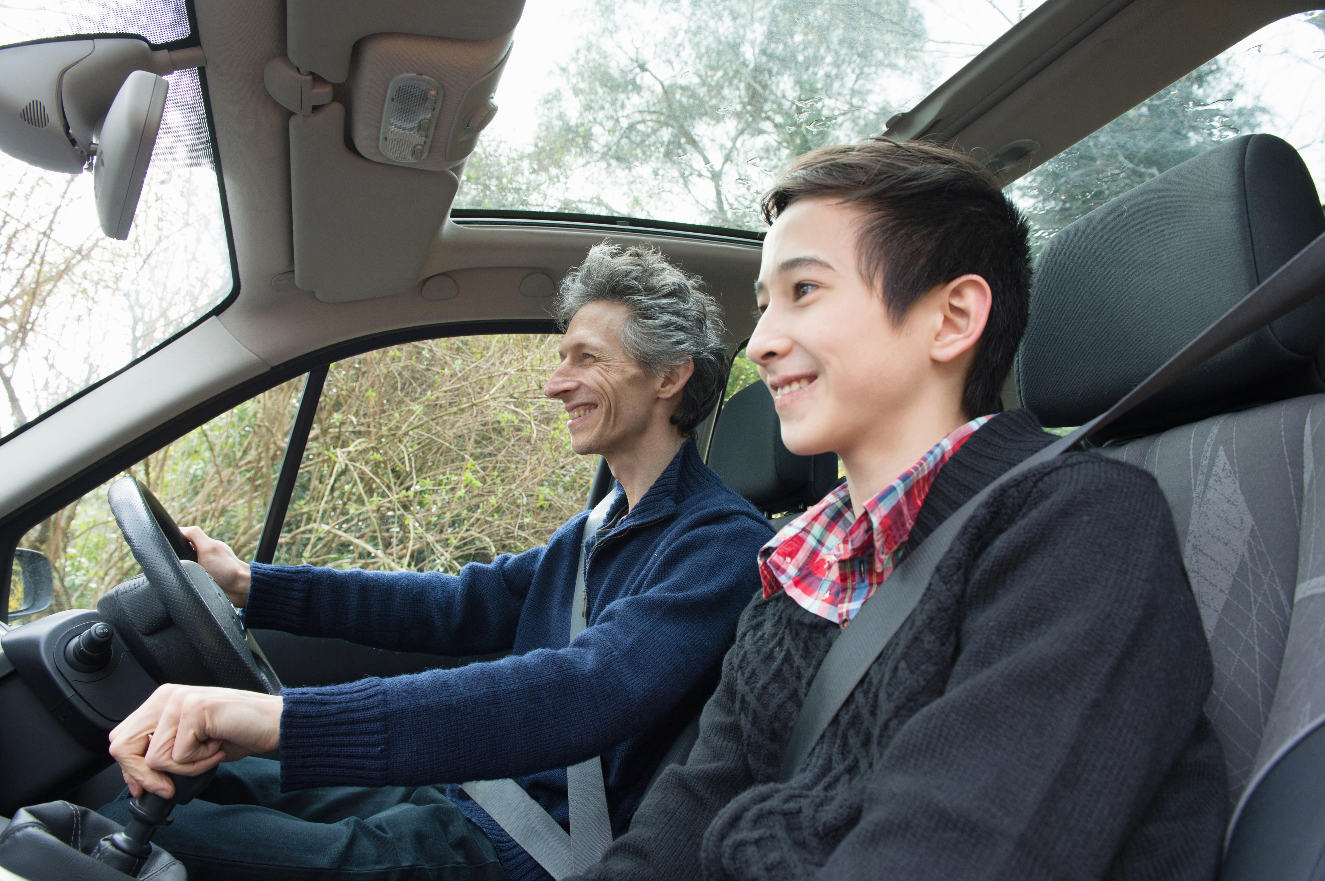 Dad talking to teenage son while he drives a car 