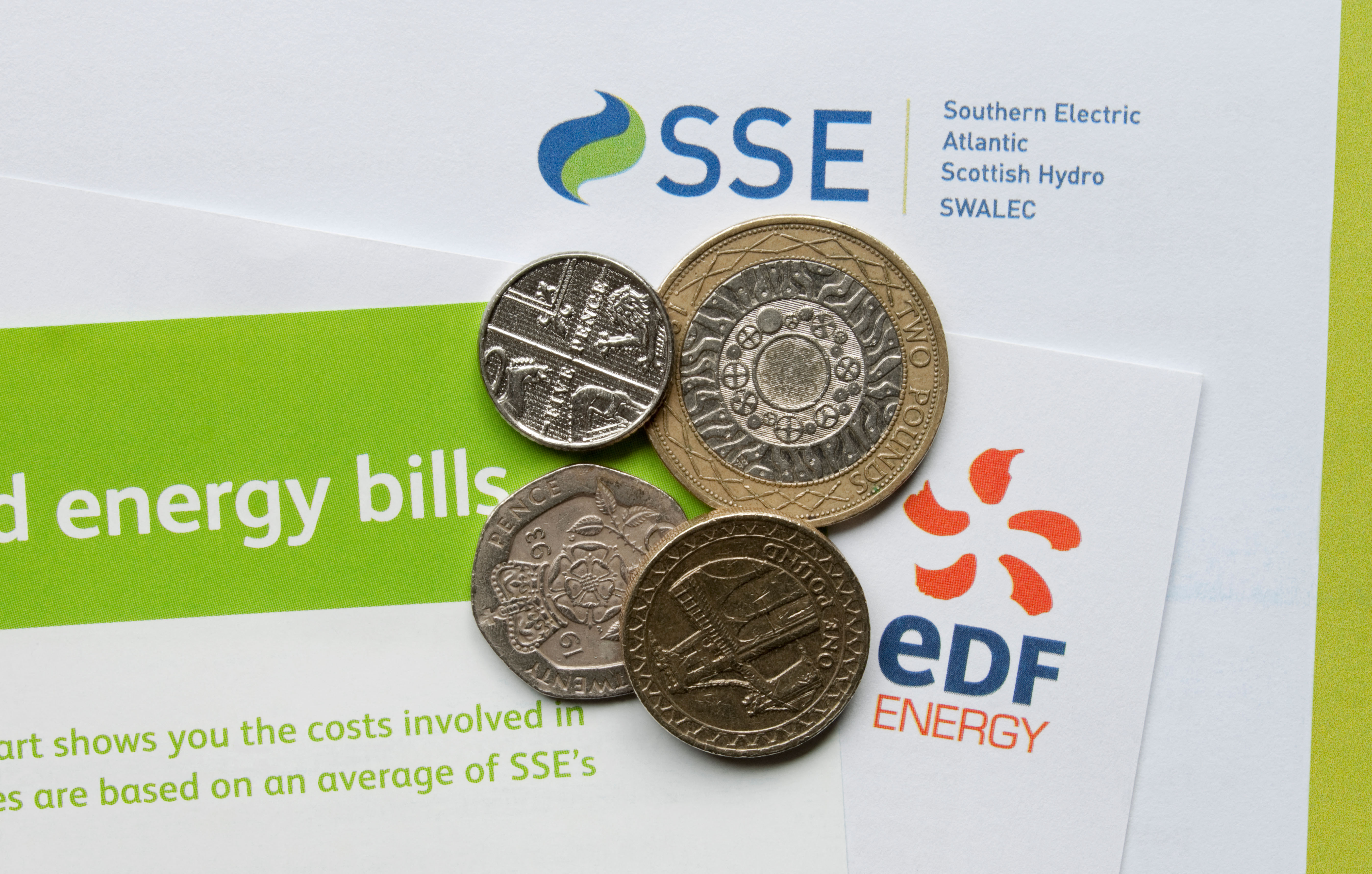  Close up of EDF Energy and SSE gas and electricity utility household bills with coins on top (