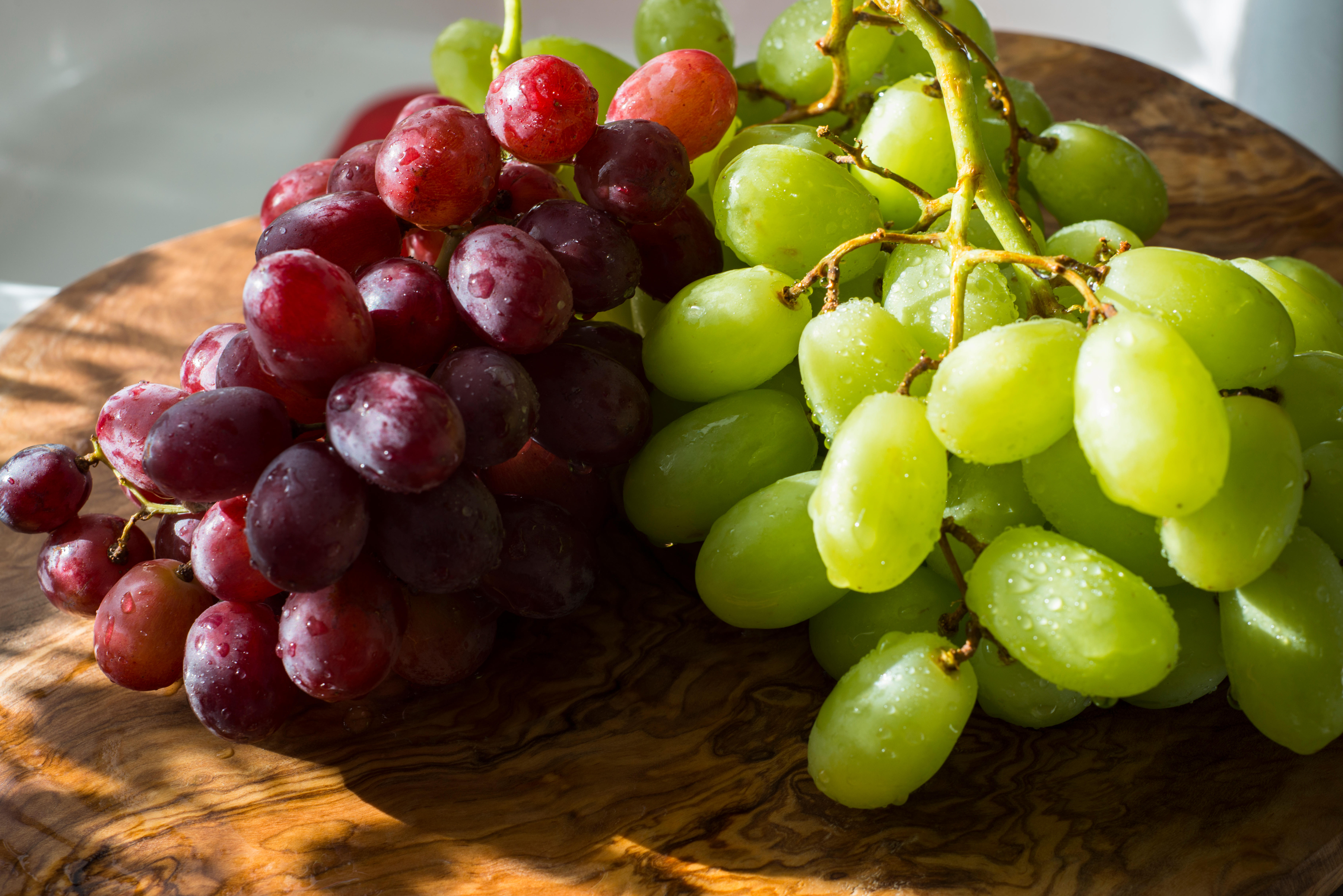 Red and green grapes on a wooden chopping board