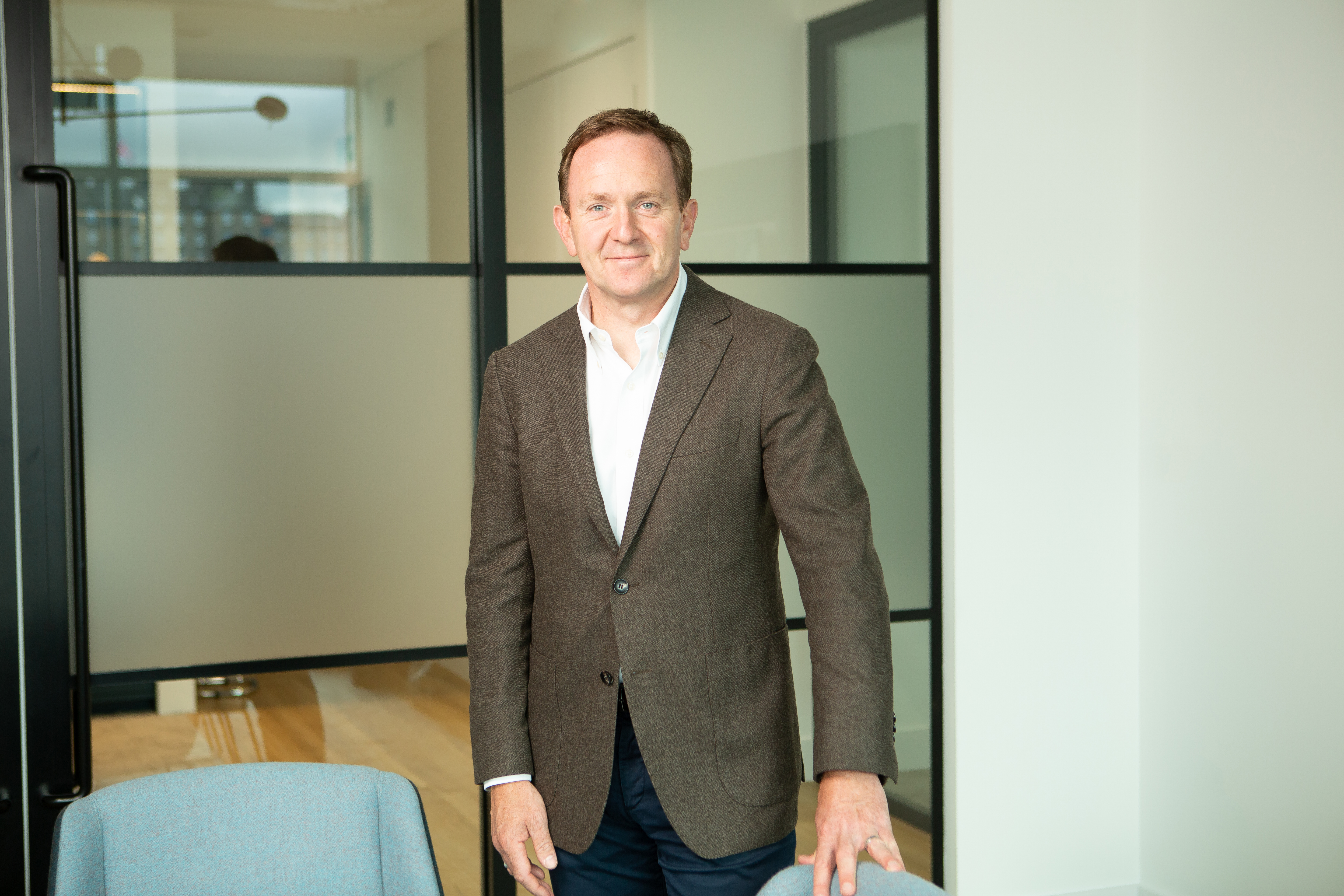 Handout photo of Malcolm Robertson smiling, while standing in an office