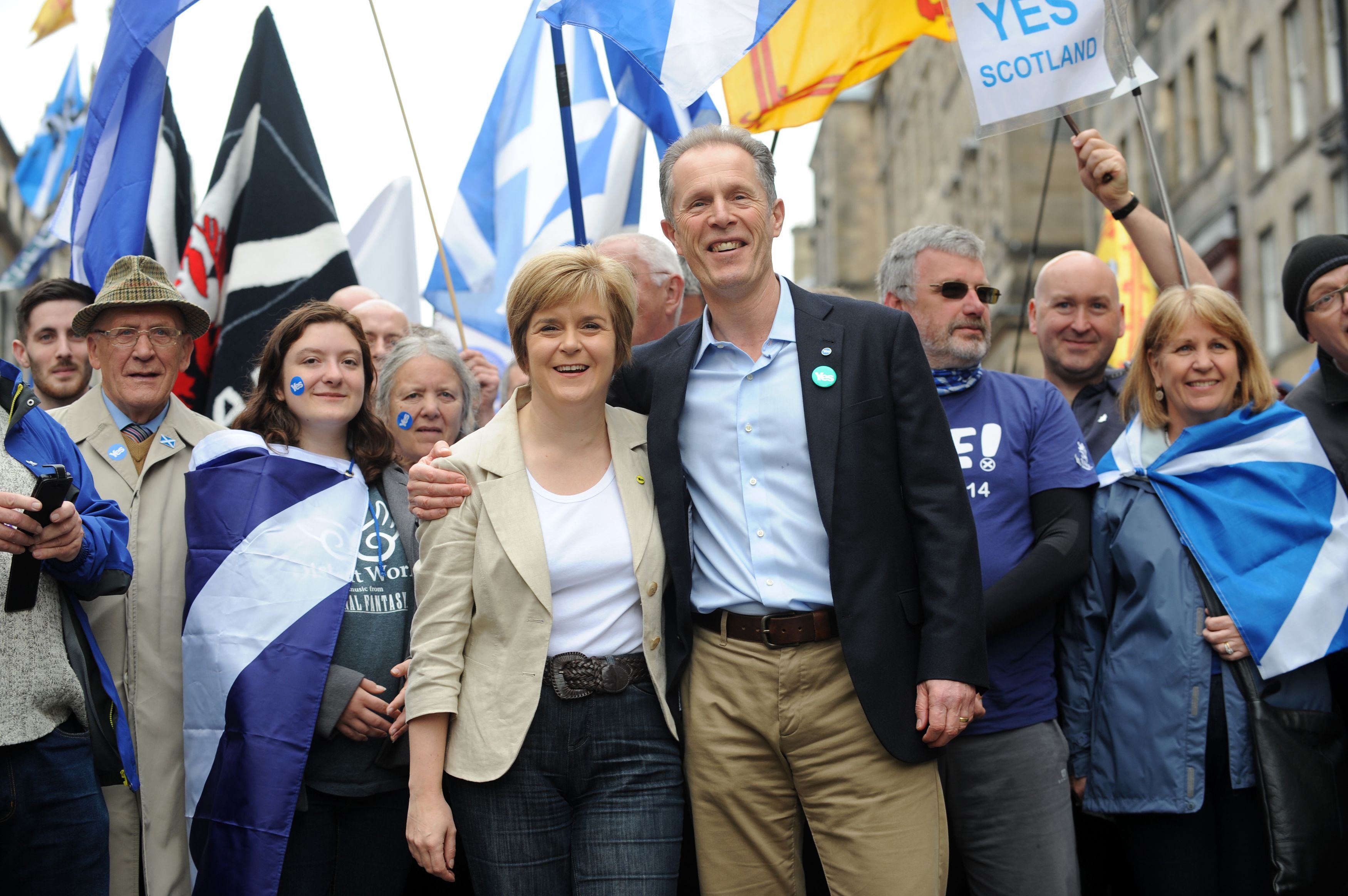 Nicola Sturgeon and Blair Jenkins smiling, while surrounded by people wearing or flying Scottish flags