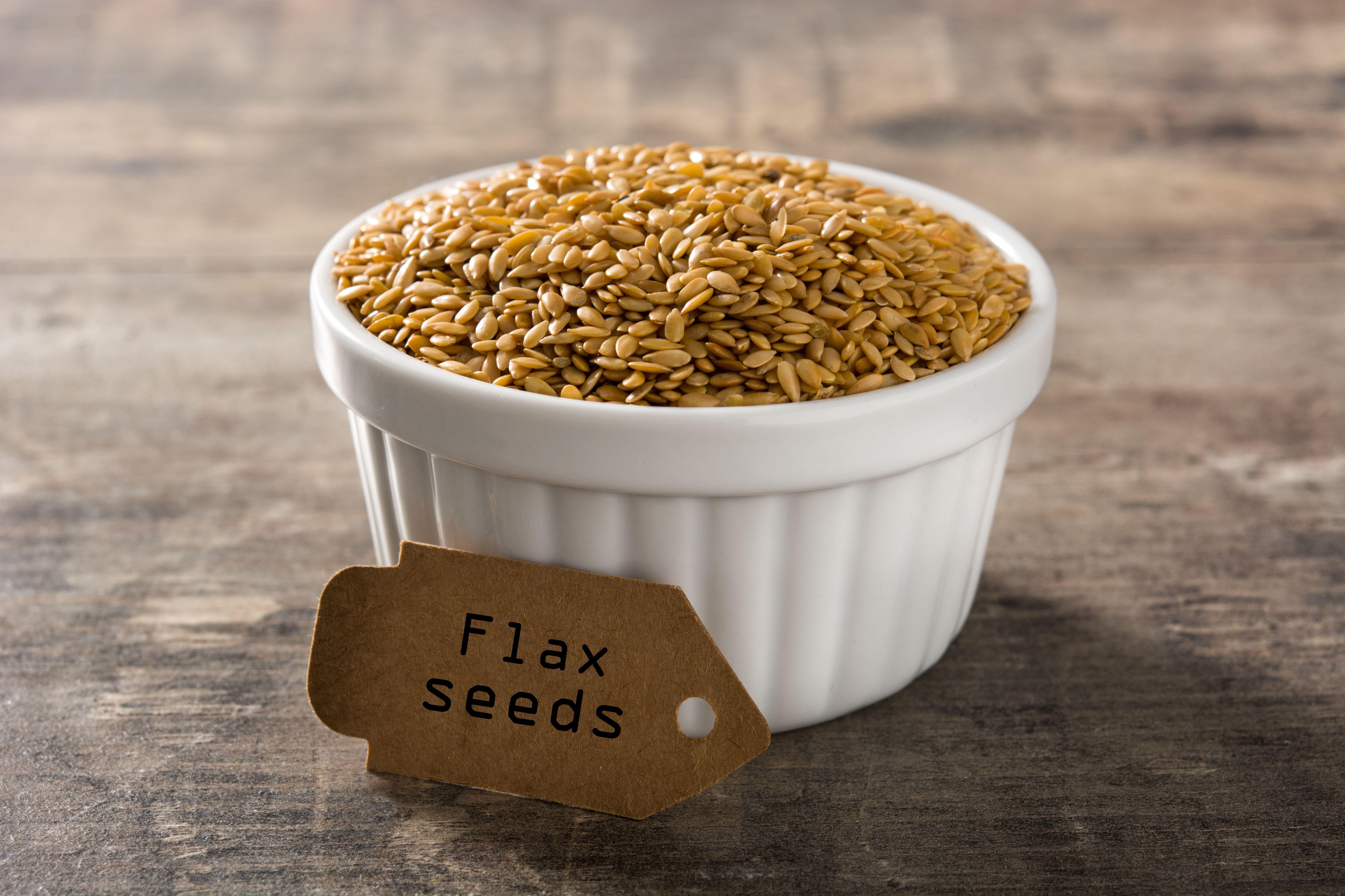 Golden flax seeds in a white ramekin on a wooden table