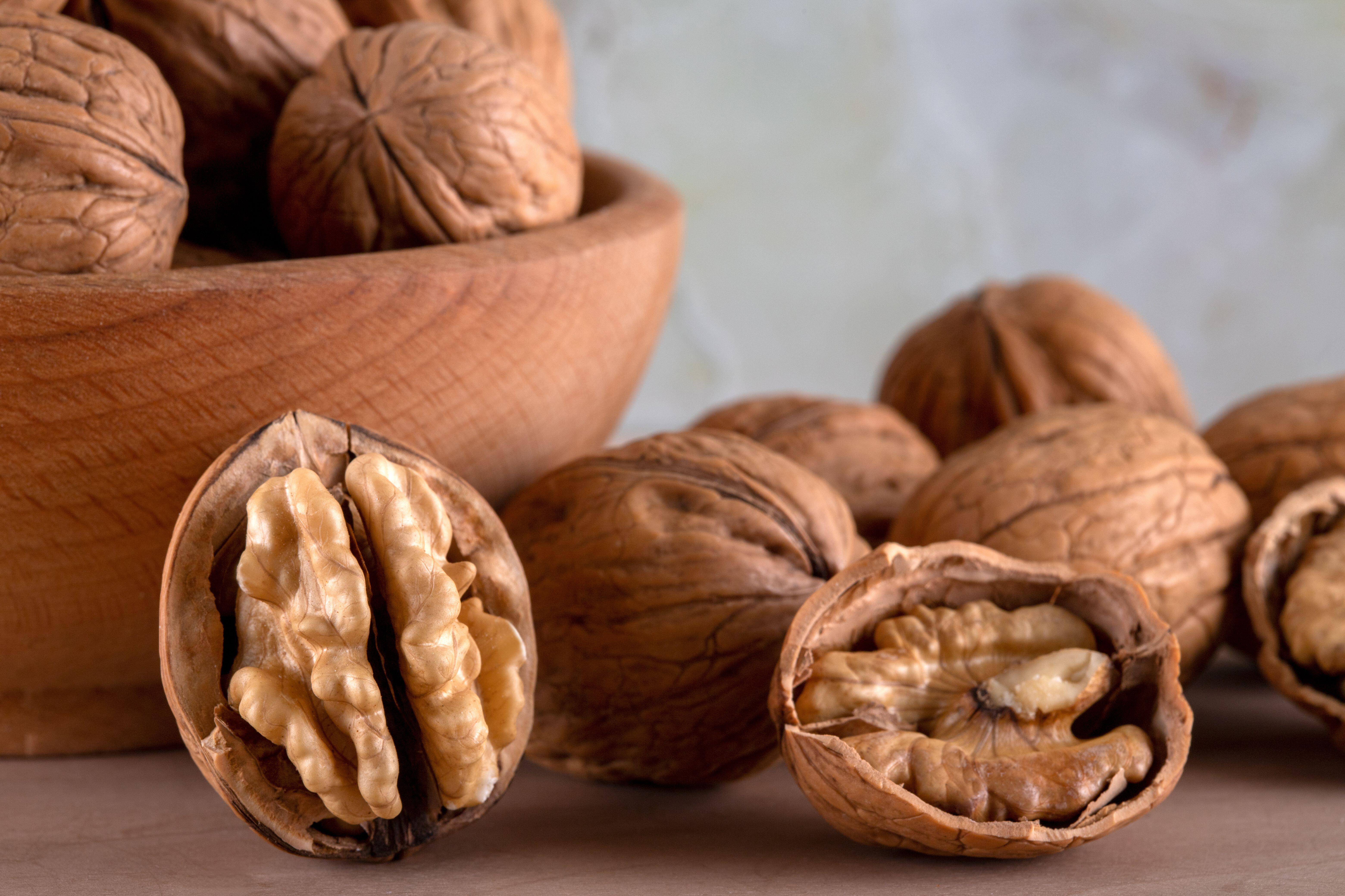 A bowl of shell walnuts and a group of broken walnuts