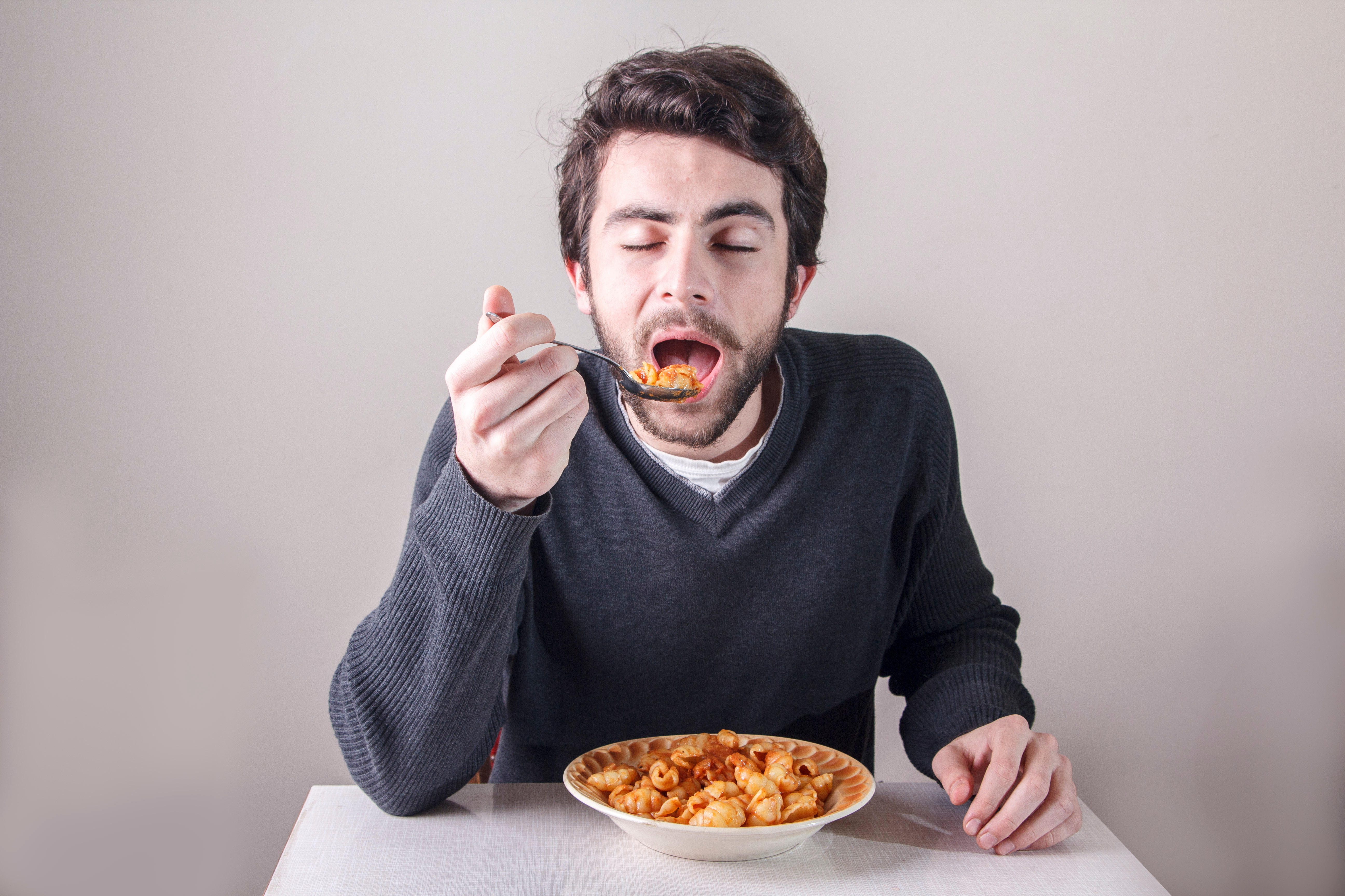 Hungry man eating bowl of pasta