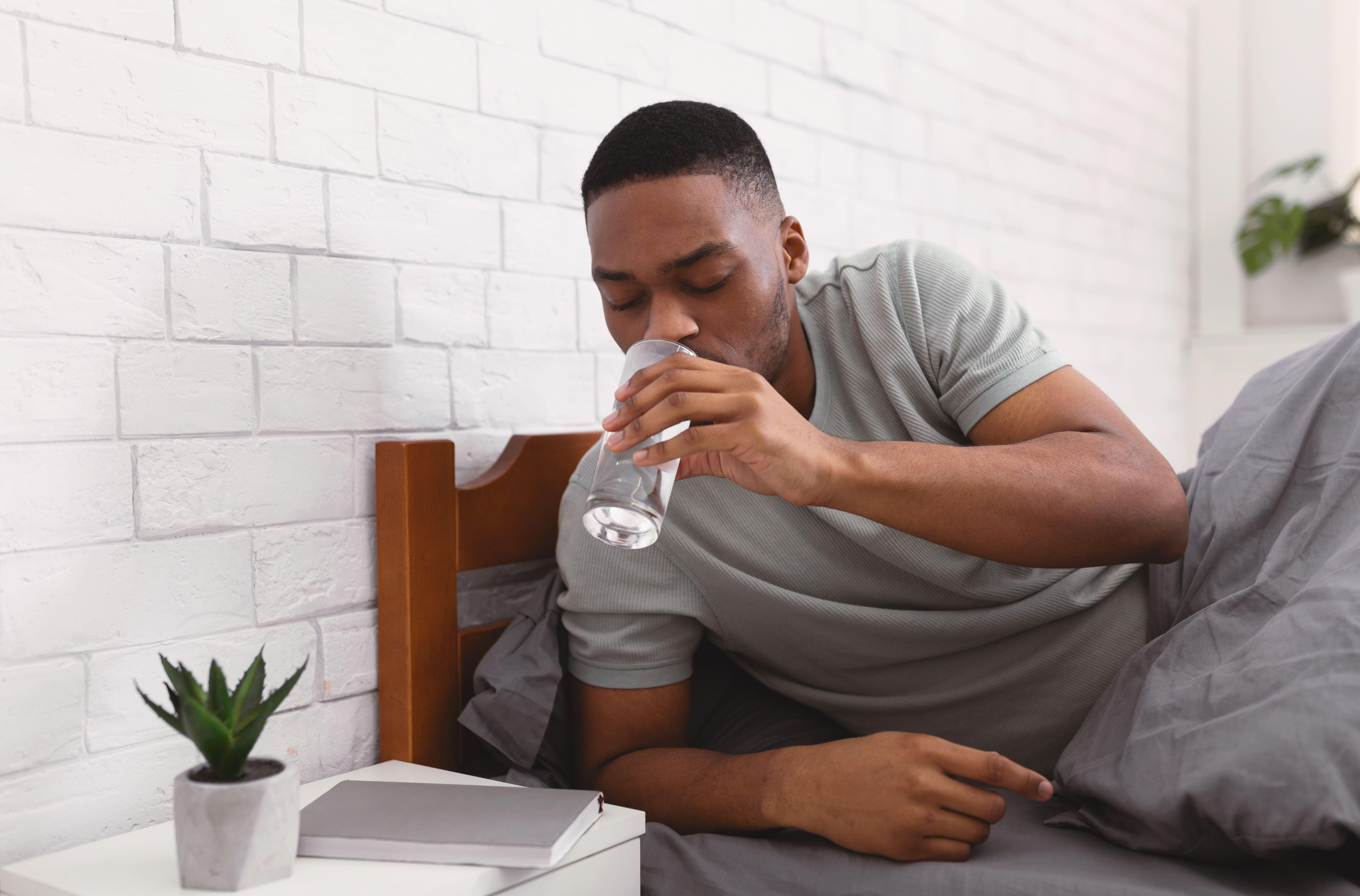 Man in bed drinking glass of water