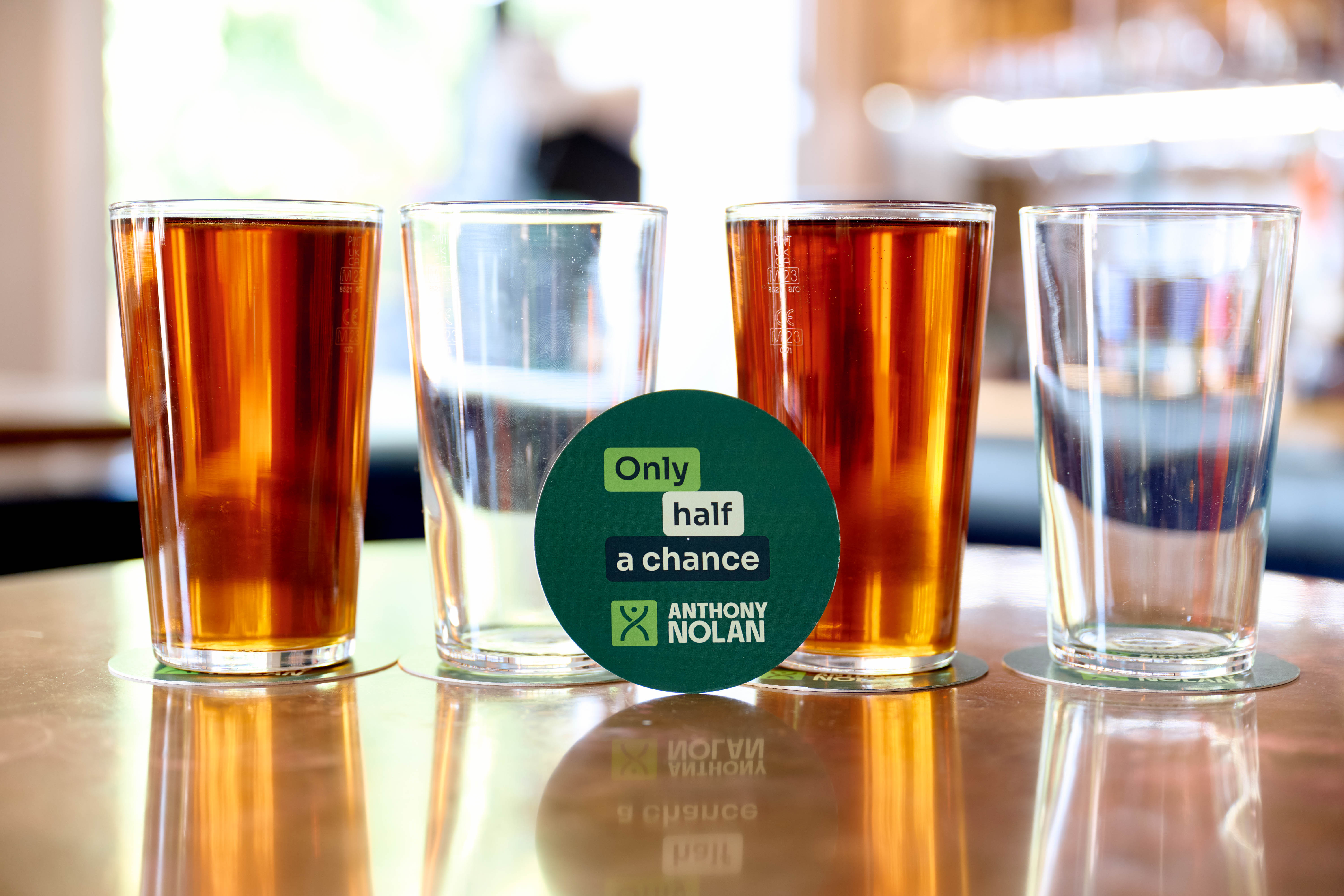 Pints of beer on a table next to a table mat featuring a campaign slogan 