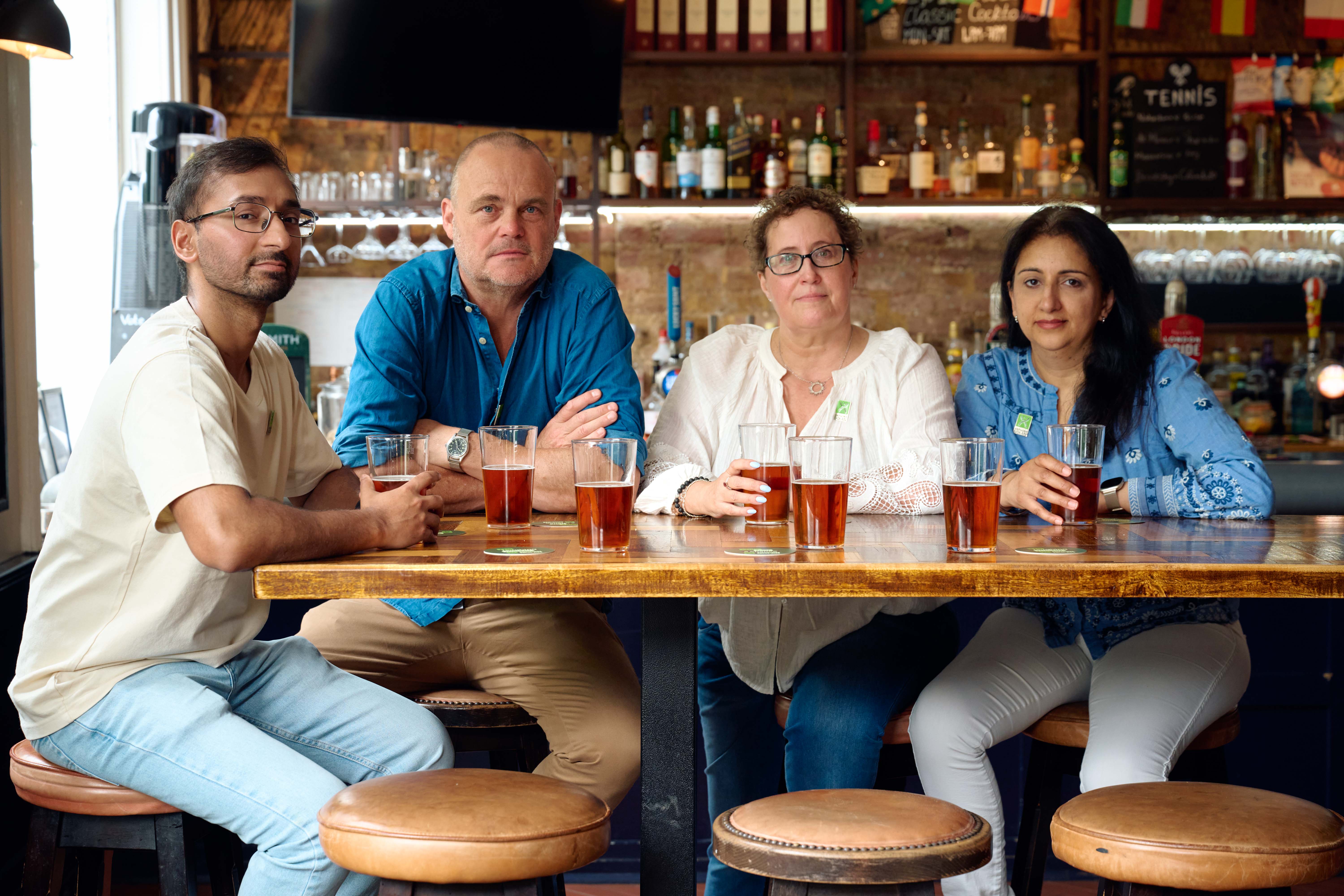 Al Murray and three others at a pub table with three empty stools