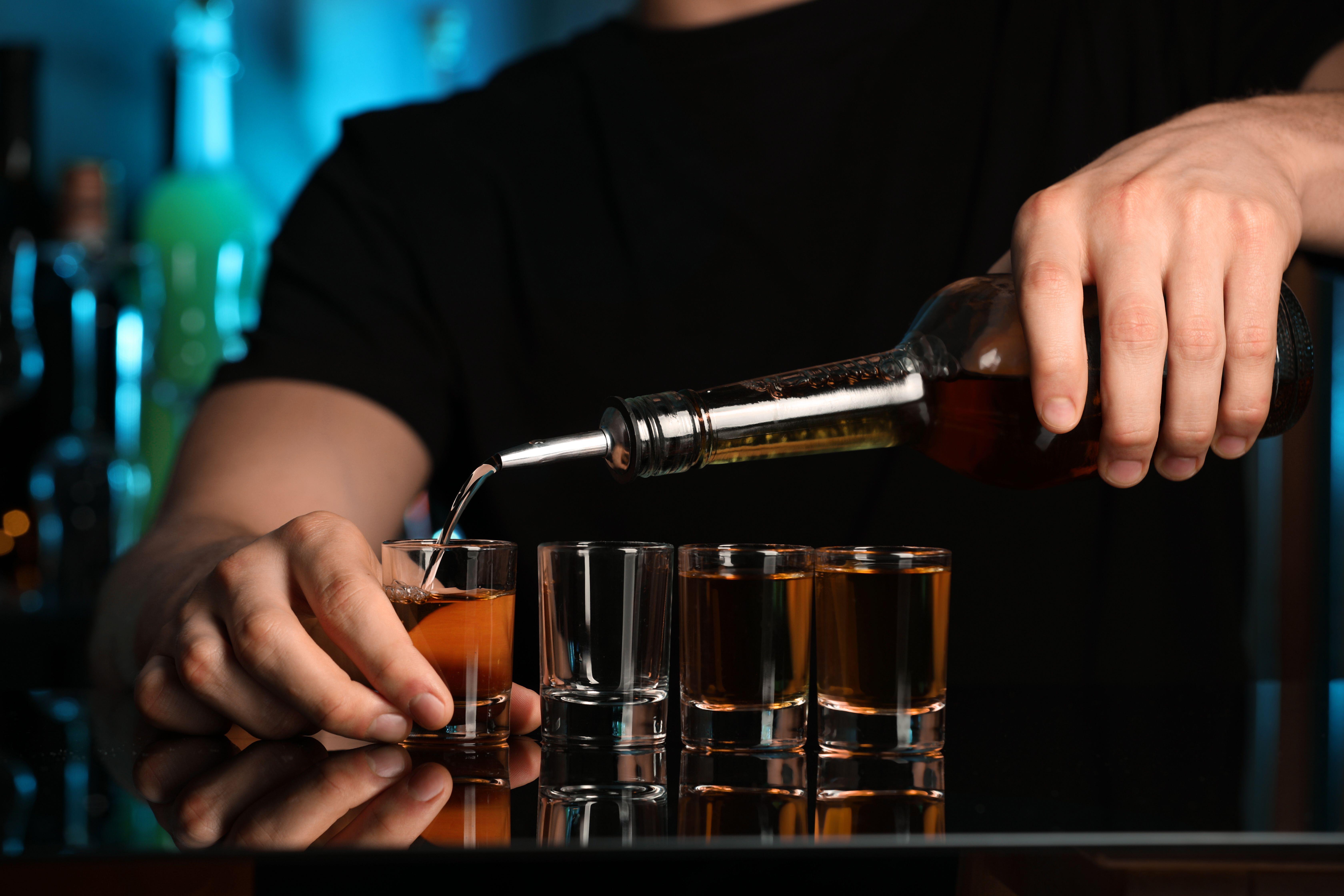 Bartender pouring alcohol drink into shot glass