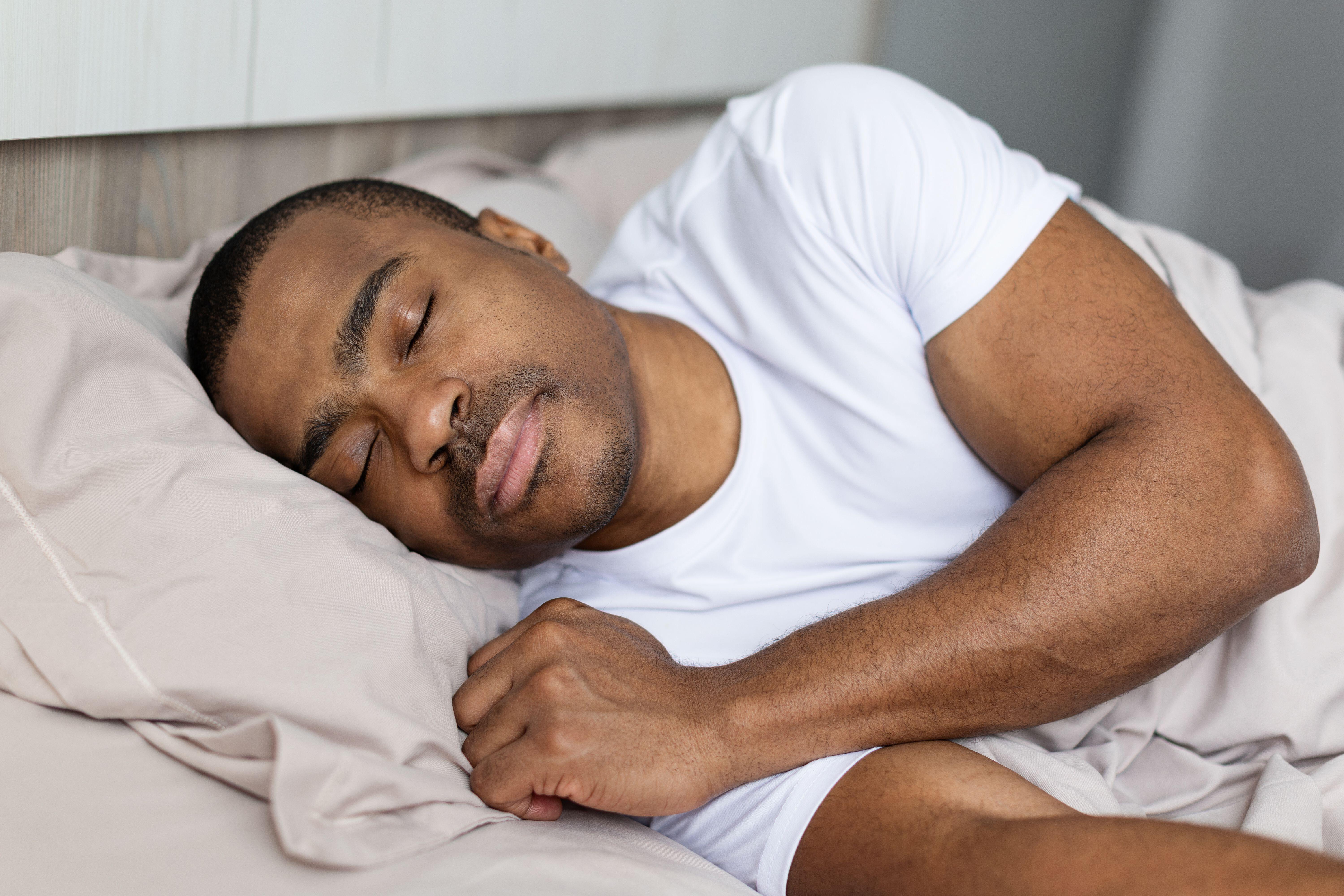 Man in white T-shirt sleeping peacefully in bed