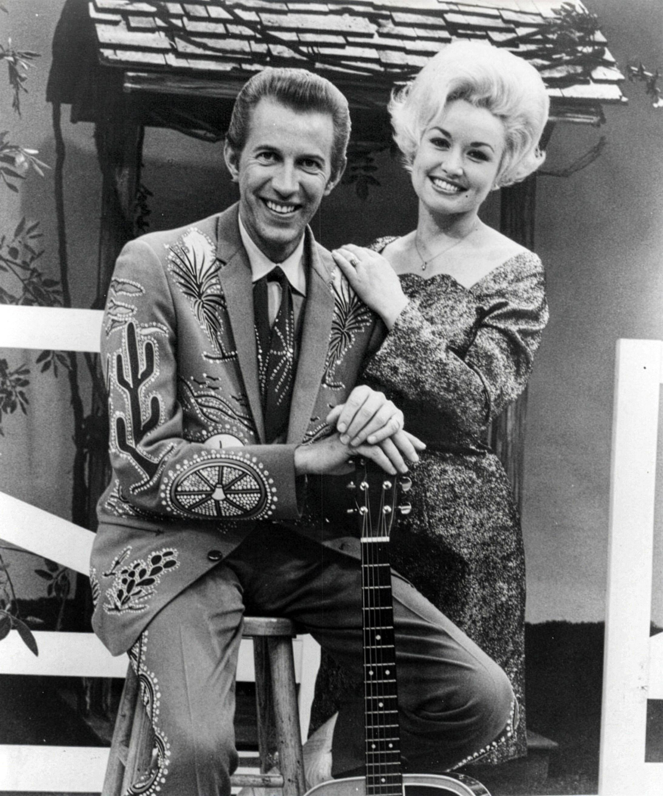 Country music stars Porter Wagoner and Dolly Parton pose together in a promotional photograph from 1969