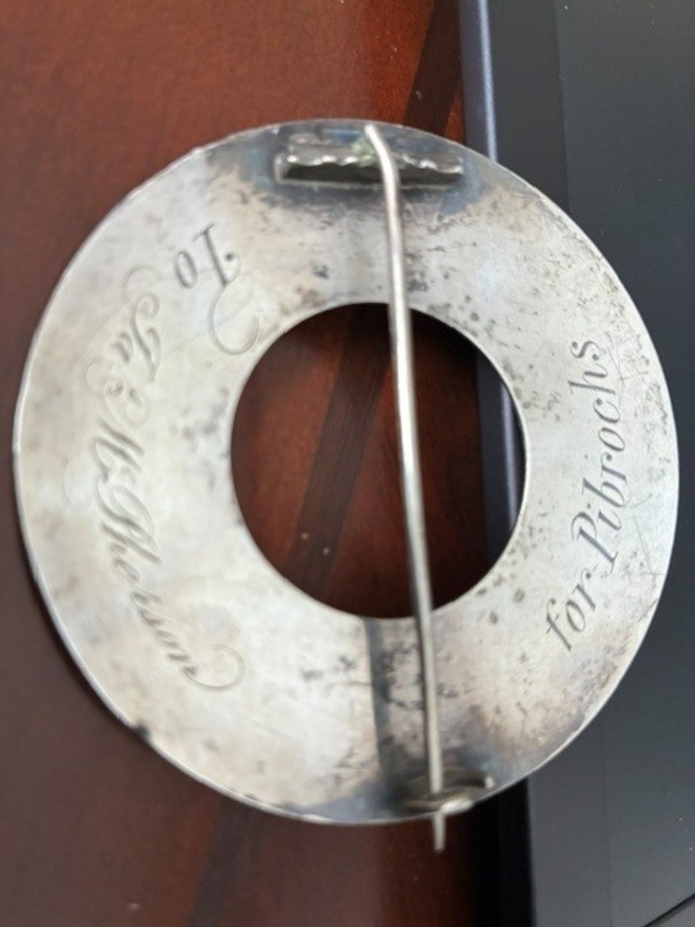 View of the reverse of a silver brooch, which shows an inscription