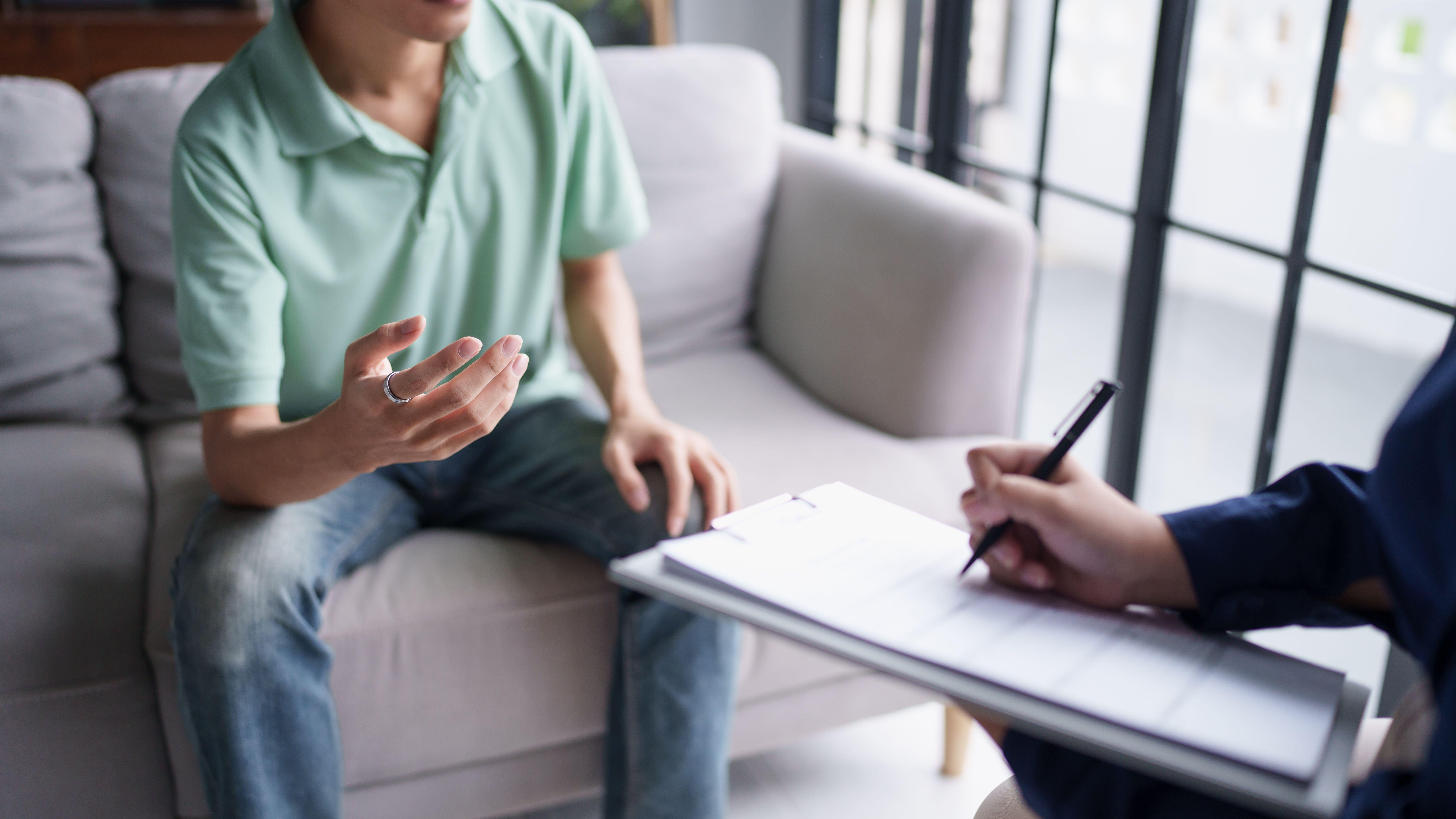 Therapist taking notes while talking to male patient