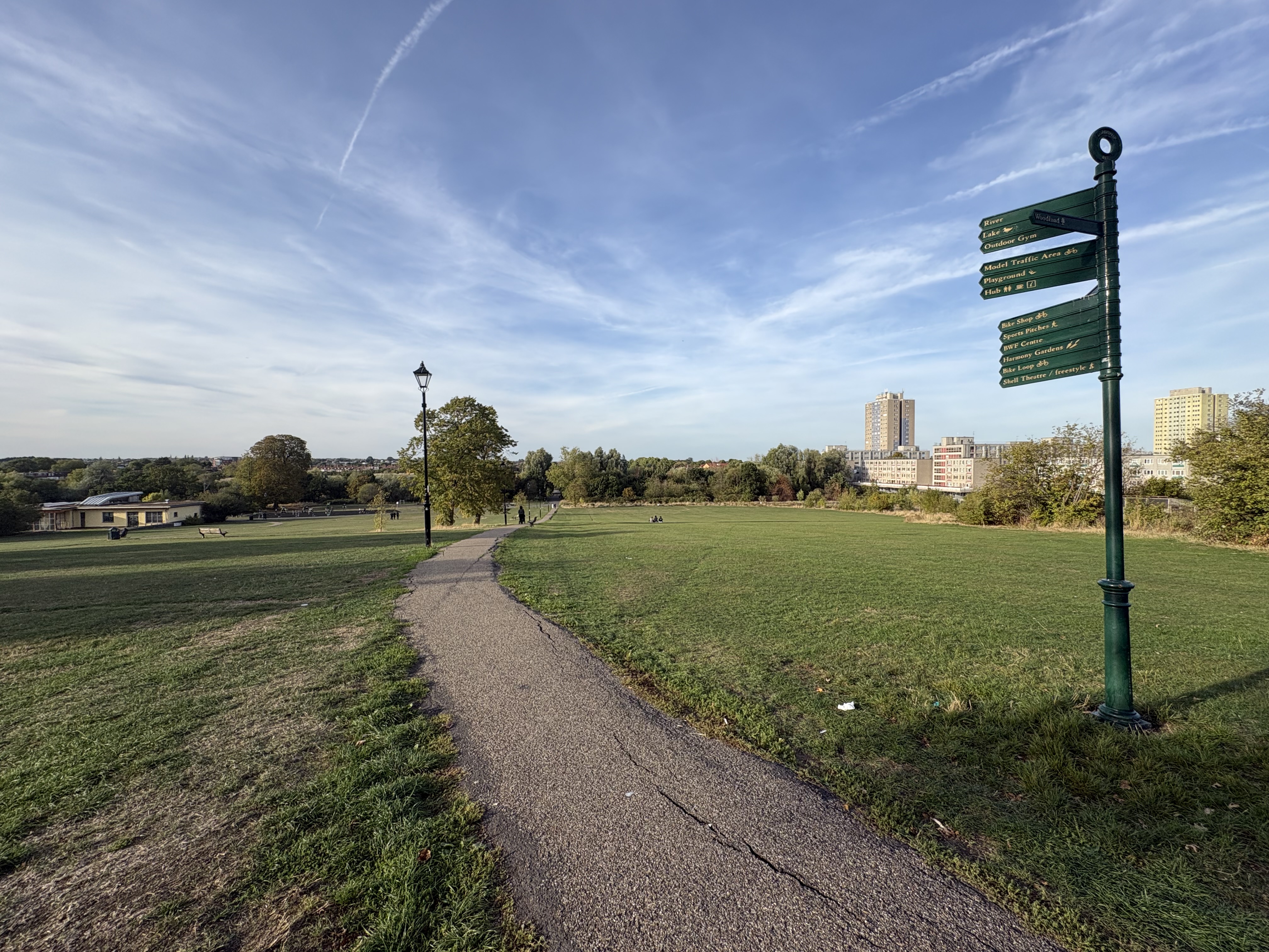 A path leading into a park with a signpost with a number of facilities highlighted and tower blocks in the distance (Emily Beament/PA)