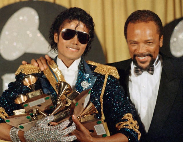 Michael Jackson, left, holds eight awards as he poses with Quincy Jones at the Grammy Awards in Los Angeles in 1984