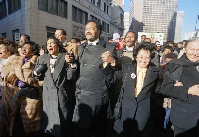 Coretta Scott King holds hands while singing with the Rev Jesse Jackson and Christine Farris, the sister of Dr Martin Luther King Jr