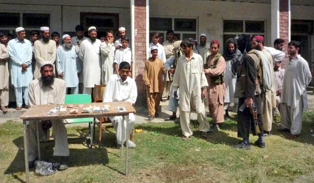 Armed supporters of an outlawed militant group Tehreek-e-Taliban Pakistan, right, escort one of three thieves for their trial by Taliban on the outskirts of Matta, an area of Pakistan’s Swat district, in 2008