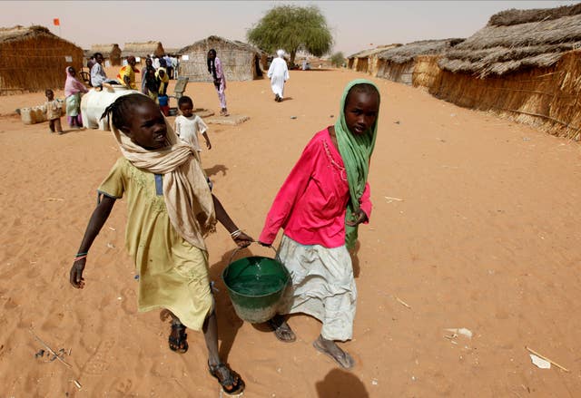 Sudanese refugee girls carry water supplies near a polling station in the refugee camp of Zamzam, on the outskirts of El Fasher, Darfur, Sudan