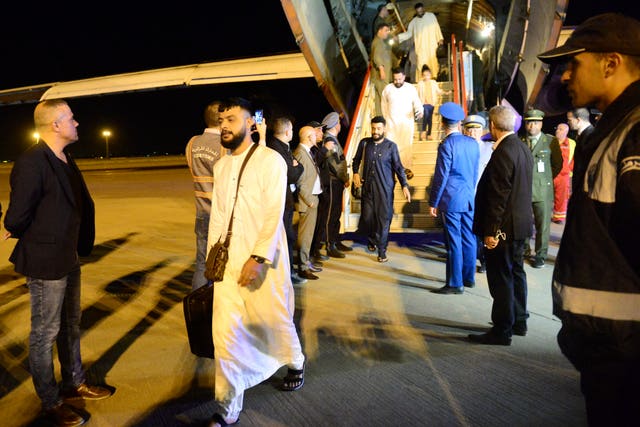 People disembark a military plane after arriving from Khartoum at the Houari-Boumediene airport in Algiers