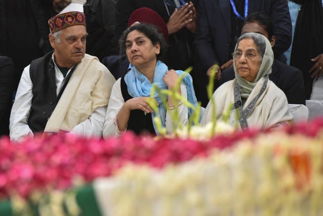 Three people alongside a decorated coffin