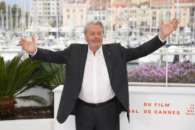 Alain Delon smiling with arms raised