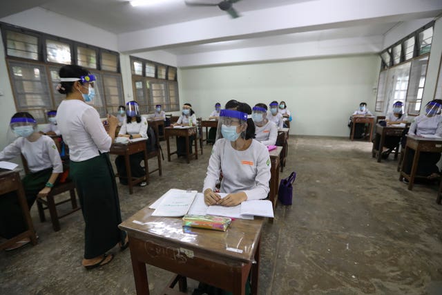 A teacher and students wearing face shields and masks attend a class