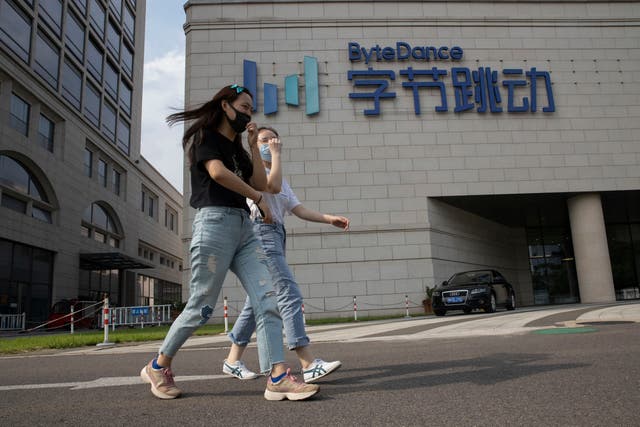 Two people pass the headquarters of ByteDance in Beijing