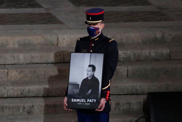 A Republican Guard holds a portrait of Samuel Paty