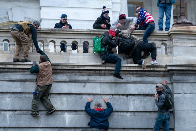 Rioters loyal to President Donald Trump climb the west wall of the the US Capitol