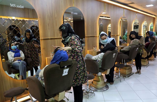 Beauticians put makeup on customers at a beauty salon in Kabul 
