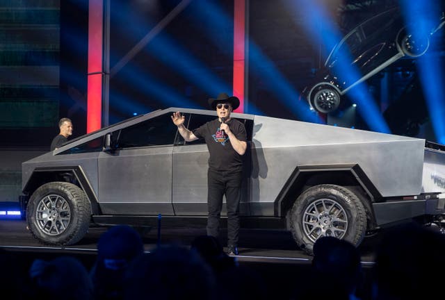 Tesla CEO Elon Musk speaks in front of a car