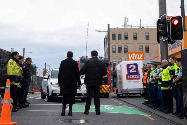 Fire and police investigators form a guard of honour as the first body is removed from the building