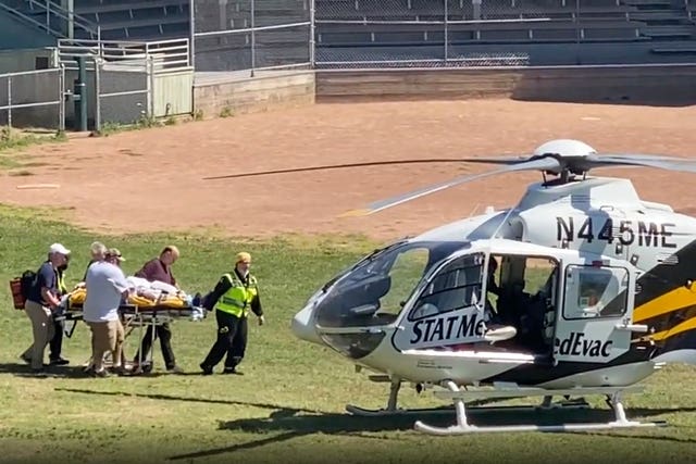 Sir Salman Rushdie is taken on a stretcher to a helicopter 