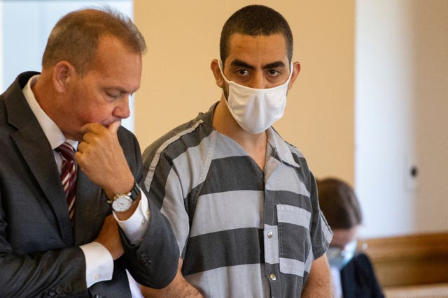 Hadi Matar in a striped prison jumpsuit and facemask