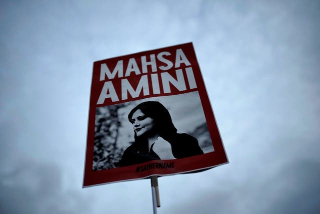 A woman holds a placard with a picture of Iranian woman Mahsa Amini during a protest against her death