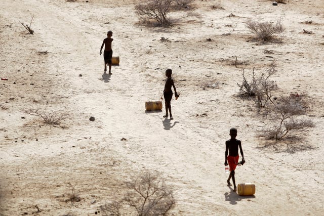 Young boys pull containers of water as they return to their huts from a well in the village of Ntabasi village amid a drought in Samburu East, Kenya, in October 2022
