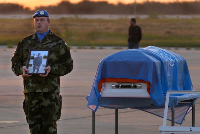 An Irish UN peacekeeper stands next to the coffin of his comrade Sean Rooney