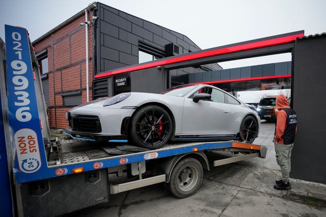 A police officer looks on as a luxury vehicle seized in a case against media influencer Andrew Tate is towed away