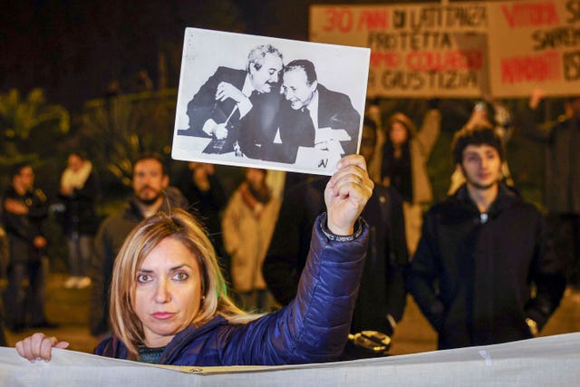 A woman displays a photograph showing top anti-mafia prosecutors Giovanni Falcone, left, and Paolo Borsellino