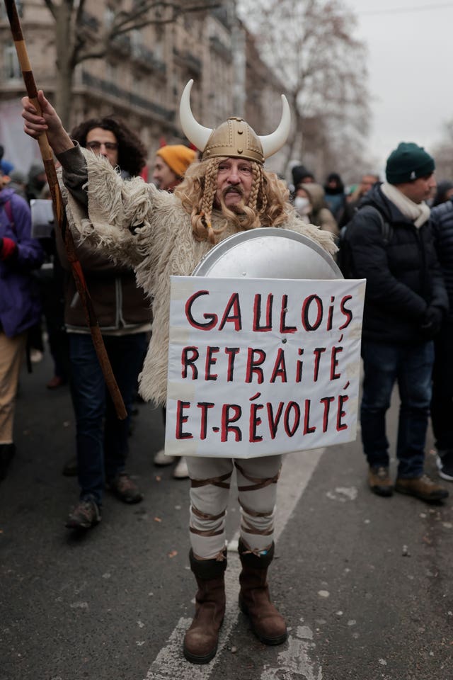 A protestor dressed like a Gallic and holding a poster reading “retired Gallic and outraged” in Paris