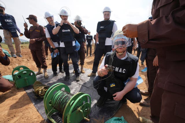 A Ukrainian deminer, second from right, listens to a Cambodia Mine Action Centre worker before a controlled explosion in the mine field at Preytotoeung village in Battambang province