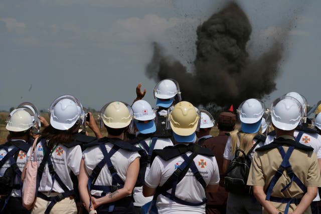 Ukrainian deminers view a controlled bomb explosion at a mine field in Preytotoeung village, Battambang province