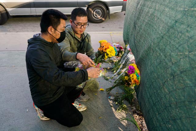 Two men place flowers near Star Dance Studio to honour victims killed in the shooting in Monterey Park 