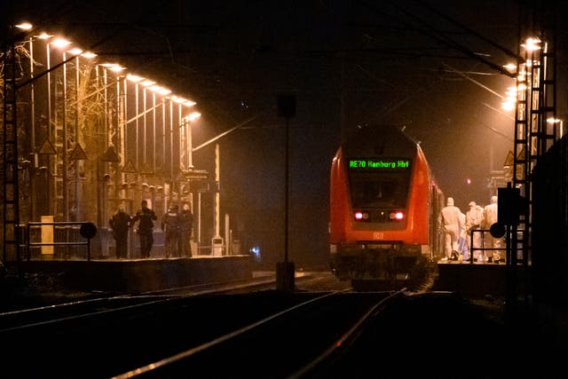 Forensics staff on a platform at a regional train, with police officers standing opposite, at Brokstedt station in Germany
